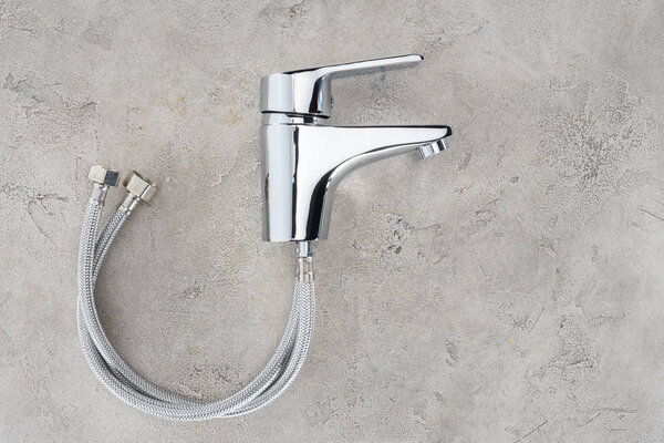 вид на водяной смеситель с гибкими трубами на бетонной поверхности
