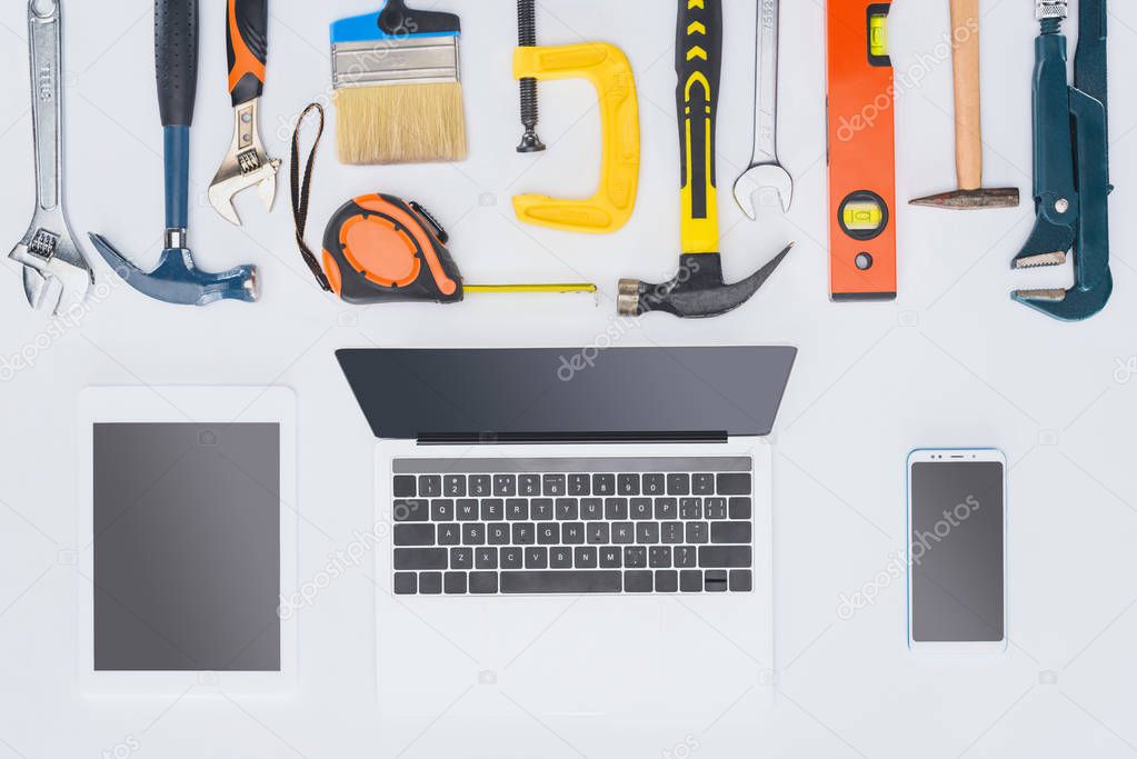 top view of laptop with various tools lying on white