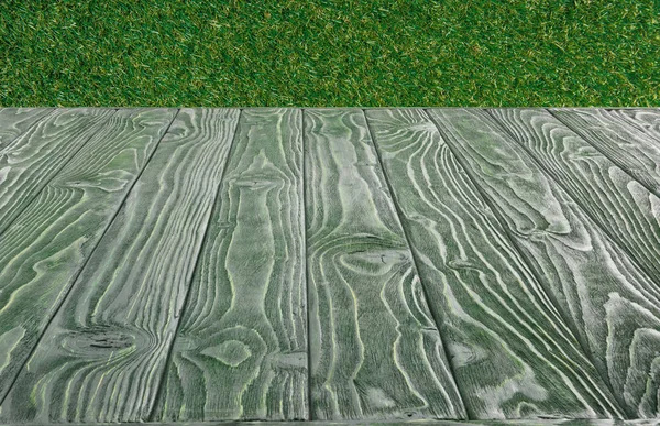 在绿色的草背景的深绿色木板表面 — 图库照片