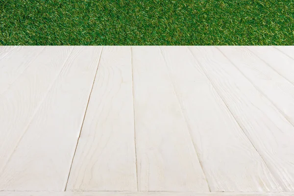 surface of white wooden planks on green grass background