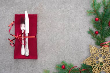 yükseltilmiş görünümü ile yaprak dökmeyen şube Noel topları ve altın Noel yıldızı tarafından dekore edilmiş kırmızı kurdele masada tarafından sarılmış bıçak ve çatal