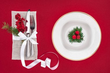 yukarıdan görüntülemek çatal, bıçak, kırmızı izole Noel topları ile şerit ve yaprak dökmeyen ağaç dalı ile plaka sarılmış kırmızı meyveler
