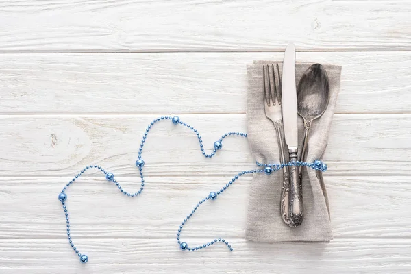 从叉子 刀和勺子上面看木桌上用装饰性的蓝色珠子包裹的东西 — 免费的图库照片