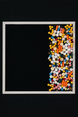 view from above of frame with pile colorful various pills isolated on black clipart