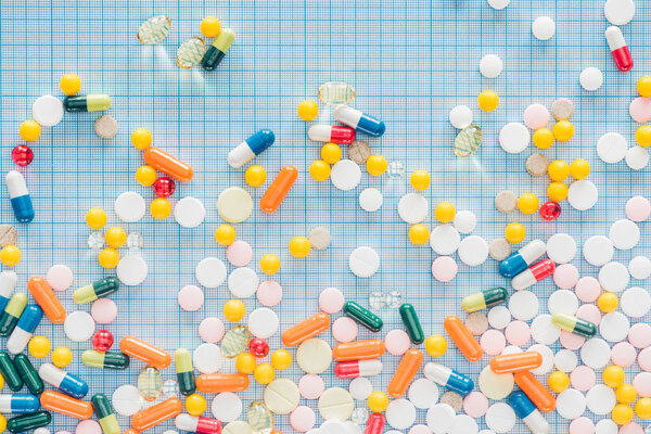 flat lay with various colorful pills on blue checkered surface