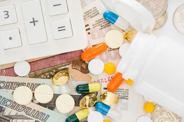 elevated view of calculator, various colorful pills and russian rubles on surface