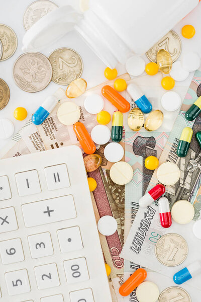 flat lay with calculator, various colorful pills and russian rubles on surface