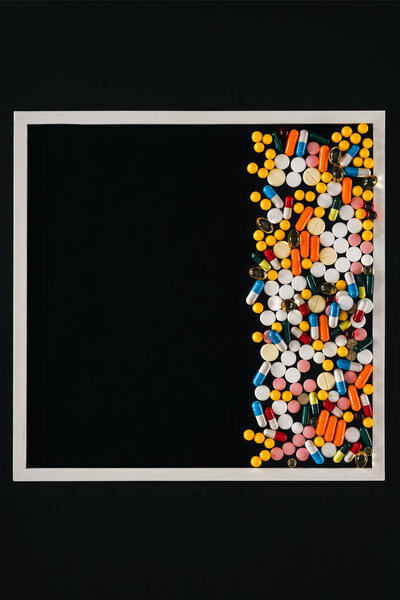 view from above of frame with pile colorful various pills isolated on black