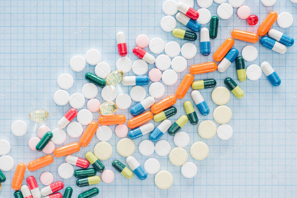 view from above of arranged various colorful pills on blue checkered surface