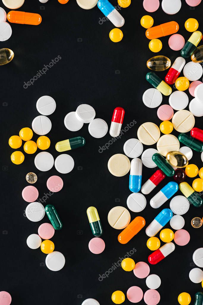 View from of pile colorful various pills isolated on black