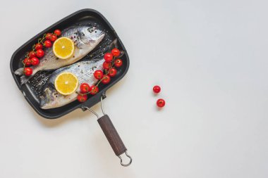 pişmemiş Balık Pişirme tepsisi içinde limon ve kiraz domates tarafından dekore edilmiş üstten görünüm