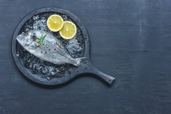 托盘的顶部视图与未煮熟的鱼与柠檬和迷迭香在桌子上 — 图库照片