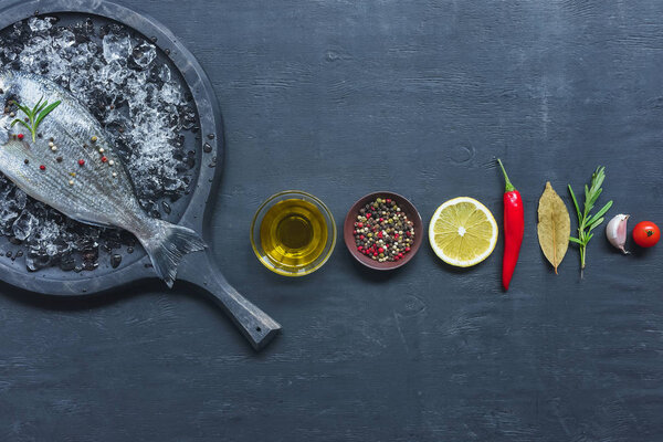 view from above of arranged ingredients near tray with uncooked fish on black table