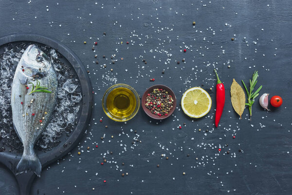 elevated view of arranged ingredients near tray with uncooked fish on black table