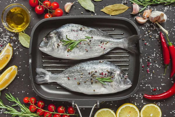 Vista Cima Peixes Não Cozidos Assadeira Cercada Por Ingredientes Mesa — Fotografia de Stock