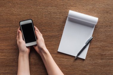 smartphone ile boş ekran, kalem, defter ile kopya alanı ahşap arka plan üzerinde tutan kişinin kısmi görünümü