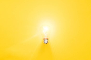 glowing light bulb on yellow background, having new ideas concept clipart
