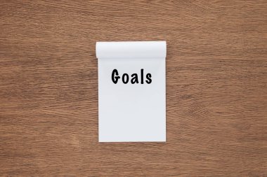  top view of notebook with 'goals' lettering on wooden background  clipart