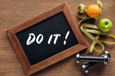 fruits, dumbbells, measuring tape and wooden chalk board with 'do it' quote, dieting and healthy lifesyle concept clipart