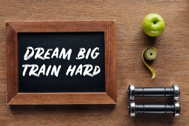 apple, dumbbells, measuring tape and wooden chalk board with 'dream big train hard' quote, dieting and healthy lifesyle concept clipart