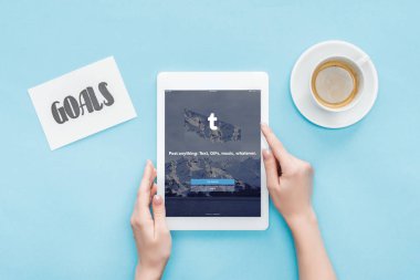 Kırpılan görünümünü erkek dijital tablet ekranında, tumblr app ile gol kartı ve kahve mavi zemin üzerine yazı kullanma