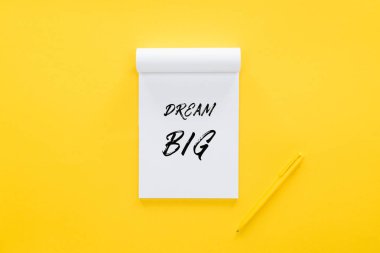 top view of notebook with 'dream big' quote on yellow, goal setting concept clipart