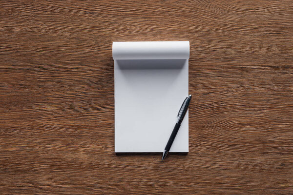 Blank notebook with pen on wooden background