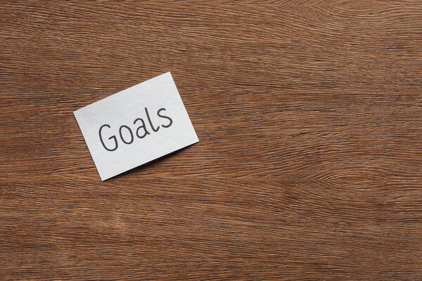 top view of 'goals' lettering on card with wooden background and copy space