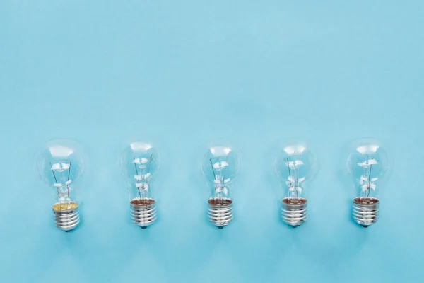 top view of light bulbs in row on blue background, having new idea concept