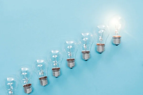 トップ ビューの行と つの電球の青色の背景色に輝く 新しいアイデアのコンセプト — ストック写真