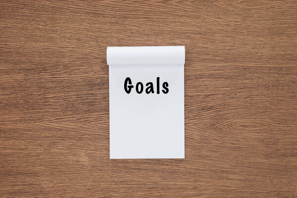  top view of notebook with 'goals' lettering on wooden background 