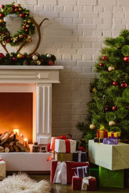 Festival süsleri ve hediye kutuları ile odun oturma odasında şömine yakın ile Noel ağacı