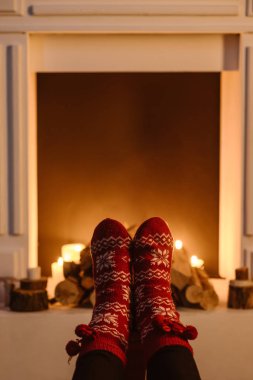 cropped view of woman in woolen winter socks with fireplace on background clipart
