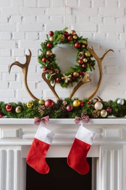 neşeli Noel çelenk süslemeleri, çorap ve geyik boynuzları üzerinde şömine şömine