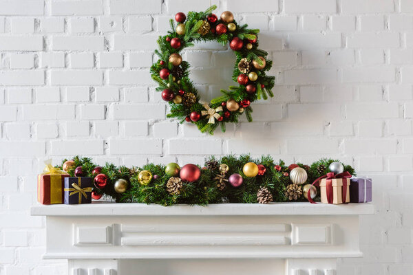 christmas wreath and decorations over fireplace mantel with white brick wall