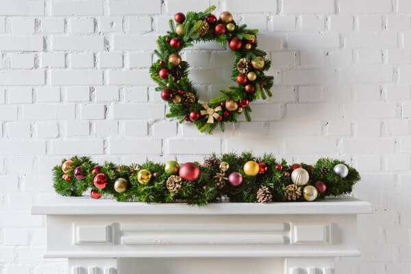 festive christmas wreath over fireplace mantel with white brick wall