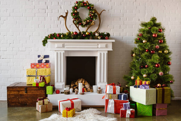праздничная гостиная с уютным камином, елка и подарки
