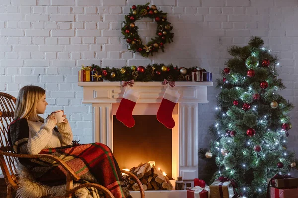 Junge Frau Auf Weidenschaukelstuhl Hält Tasse Kaffee Weihnachtlich Dekorierten Wohnzimmer — kostenloses Stockfoto