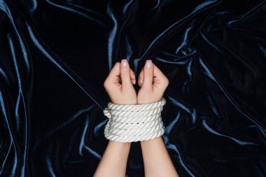 cropped view of female hands tightly bounded with rope on velvet background clipart