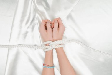 top view of female hands bounded with rope with satin cloth at background clipart