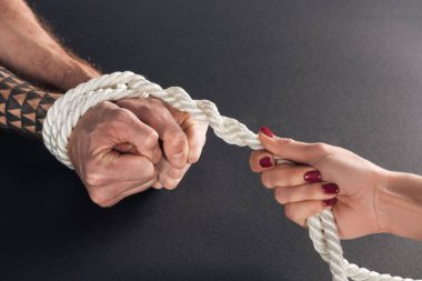 cropped view of woman holding rope on male hands on black background clipart