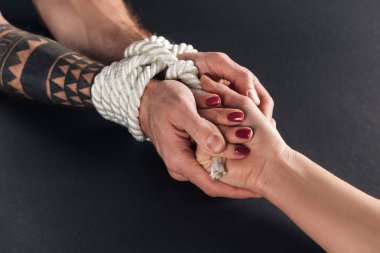cropped view of bound man holding female hand isolated on black clipart