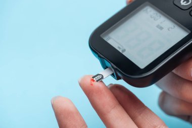 glikoz düzeyi üzerinde mavi arka plan izole şeker ölçüm test parmaklar kısmi görünümünü