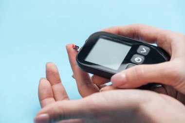 glikoz düzeyi ile mavi arka plan üzerinde şeker ölçüm test eller görünümünü kırpılmış