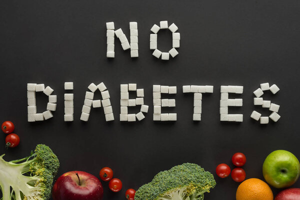 "no diabetes" lettering made of sugar cubes among fruits and vegetables on black