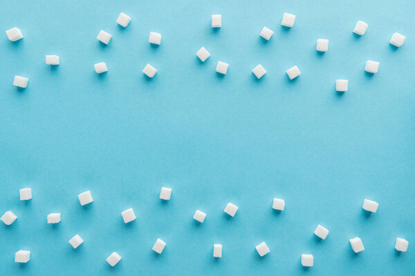top view of white sugar cubes with copy space on blue background