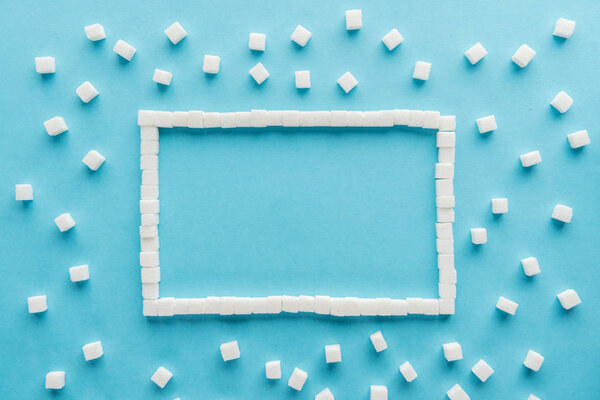 flat lay of frame made of sugar cubes with copy space on blue background