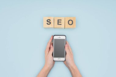 Smartphone açık mavi renkli ellerinde tutan kadının üstten görünüm 