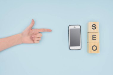 Kadın el smartphone ve açık mavi renkli küpleri işaret üstten görünüm 