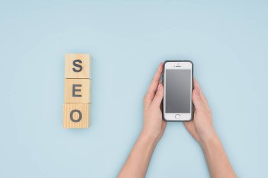 Üstten görünüm açık mavi renkli ahşap bloklar yakınındaki smatphone tutan kadın 